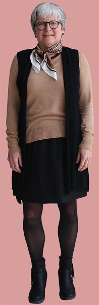 Walker wears a brown sweater paired with a black cardigan and skirt for her second outfit of the week.