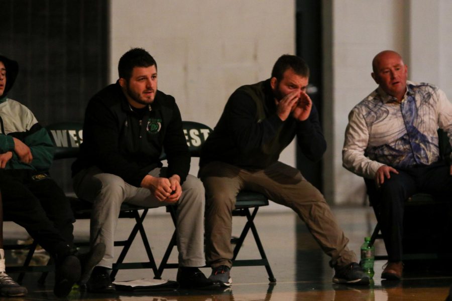 Second-year head coach Nate Moore shouts encouragment from the bench during the team's home opening wrestling meet against Dubuque Hempstead. 