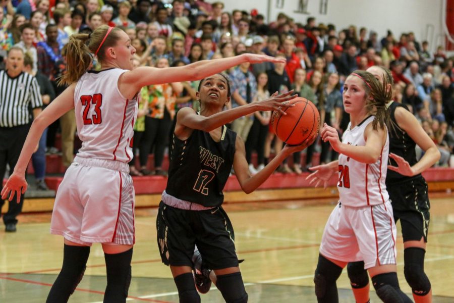 Meena Tate '23 shoots a layup around a City High defender on Dec. 14.