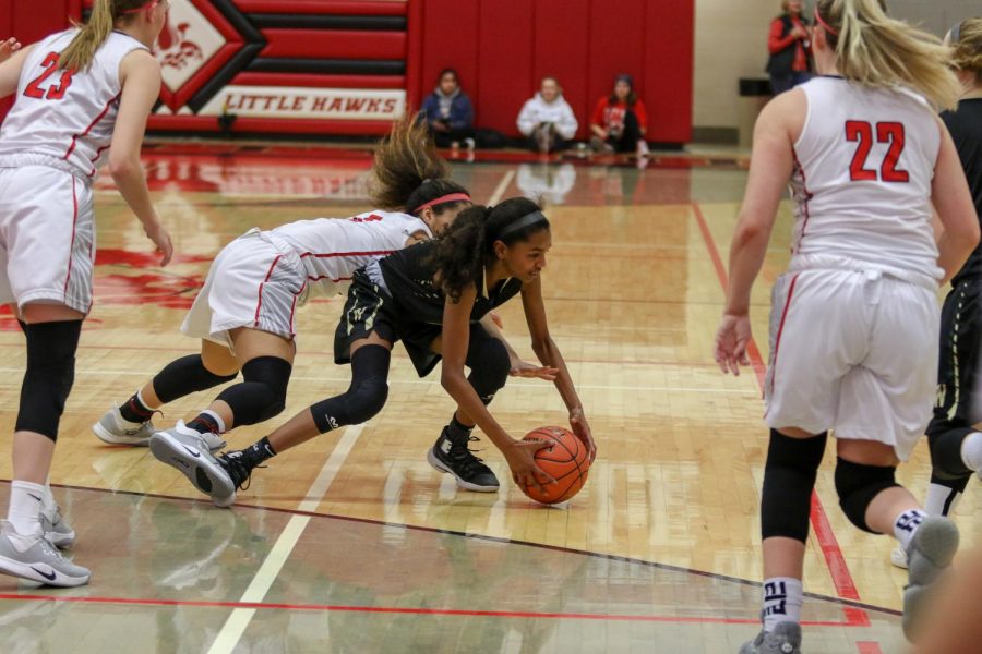 Meena Tate '23 grabs a loose ball off the floor against City on Dec. 14.