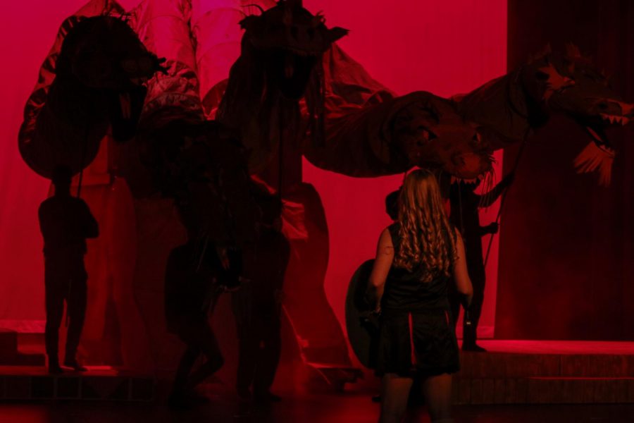 Karissa Burkhardt 20 confronts a dragon silhouetted against a dark red background while playing Agnes Evans in She Kills Monsters.