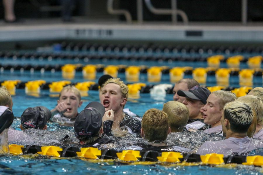 Tate Happel '20 along with his coaches and teammates celebrate their team state championship after jumping into the pool on Feb. 15.