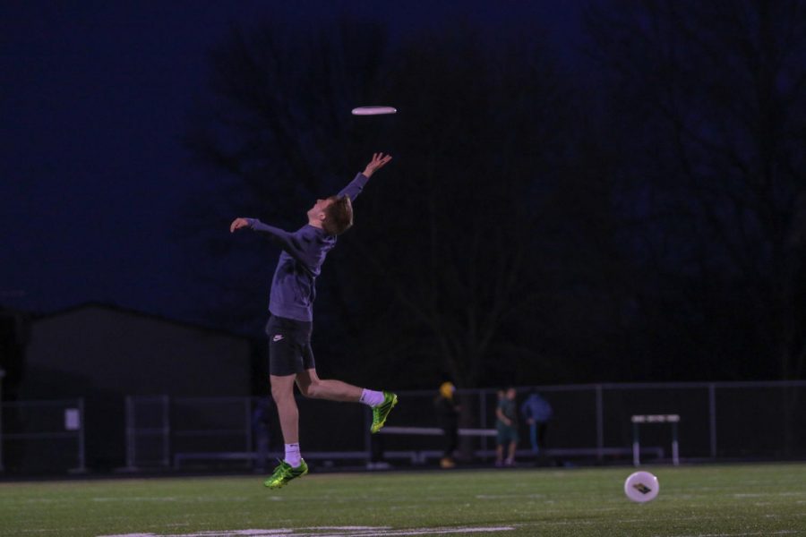 While warming up, the frisbee sails over the outstretched arms of Charlie Duffy '21.