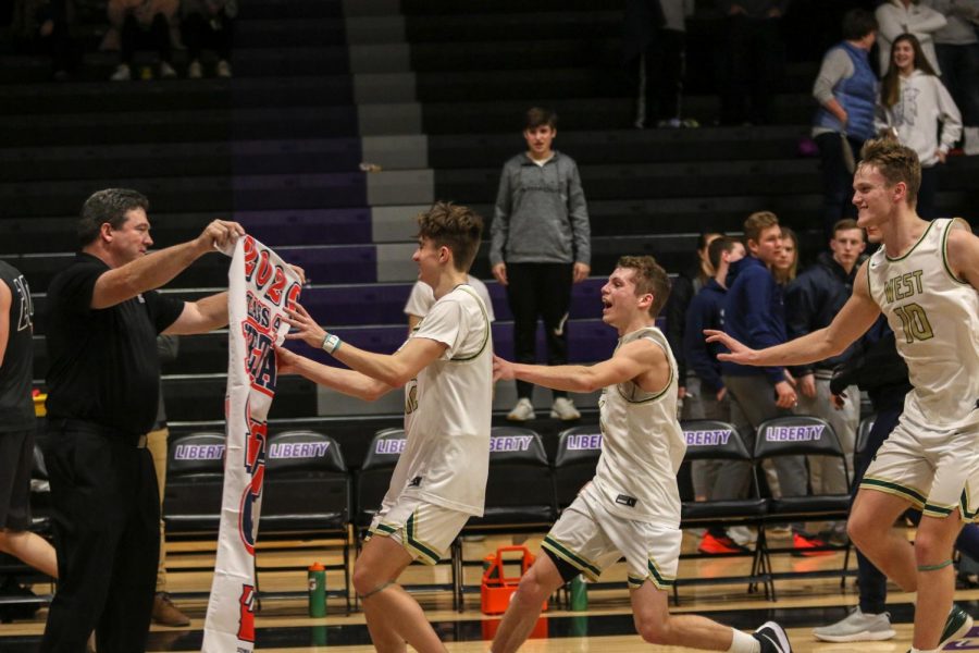 Seniors Joe Goodman, Nick Pepin, and Tate Crane run receive their state qualifier banner against Pleasant Valley on March 3.