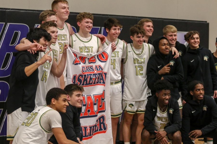 The boys basketball team poses with the state qualifier banner after defeating Pleasant Valley on March 3.