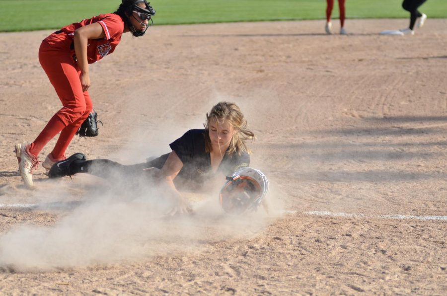 Maddie Caylor 22 aggressively slides into third base, losing her helmet in the process.