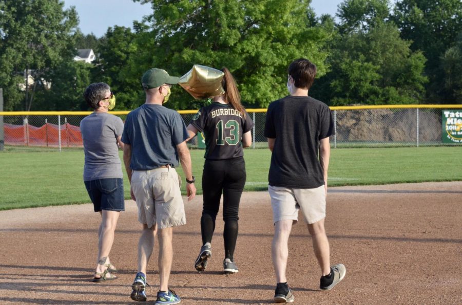 Senior Eva Burbidge walks on the field with her family to be recognized during the senior ceremony.