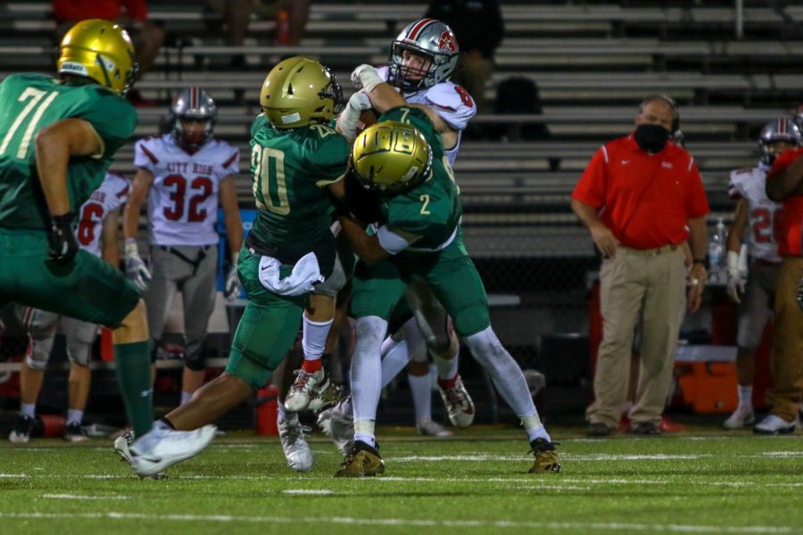 Dijon Genus '21 and Marcus Morgan '21 tackle City High wide receiver Gable Mitchell '22 during the Battle for the Boot on Sept. 4.