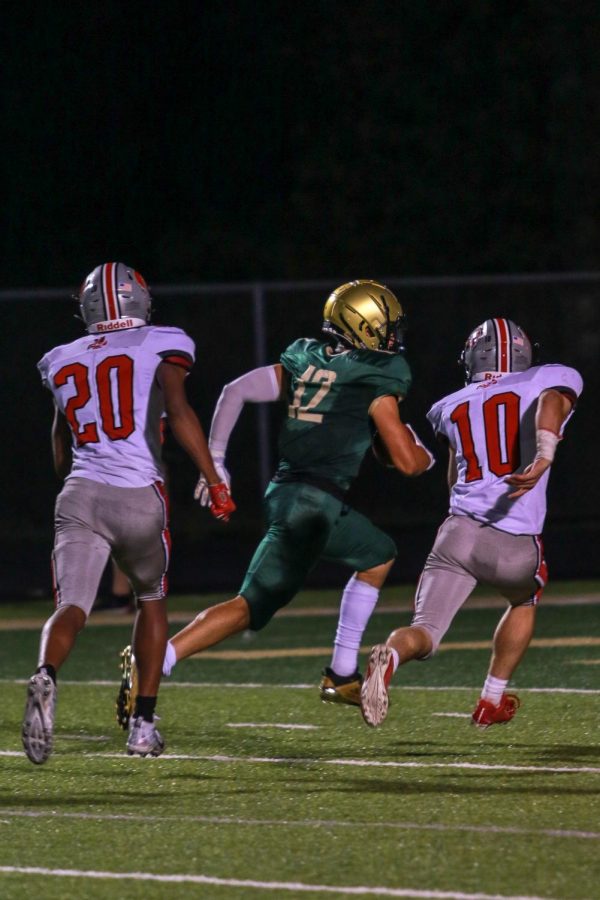 Grahm Goering '21 gets past two Little Hawk defenders for his fourth touchdown of the night during the Battle for the Boot on Sept. 4.