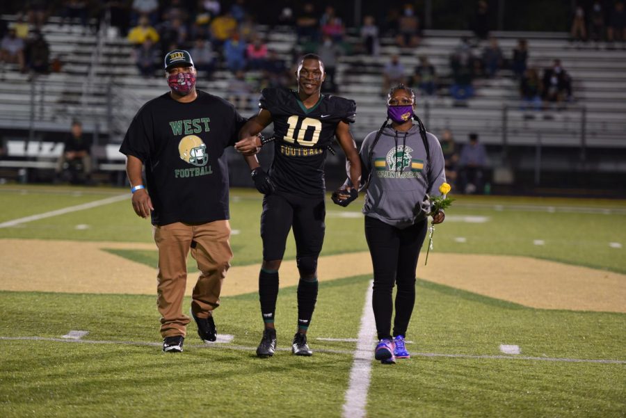 Senior Damarian Williams walks with his parents during senior night on Oct. 10.