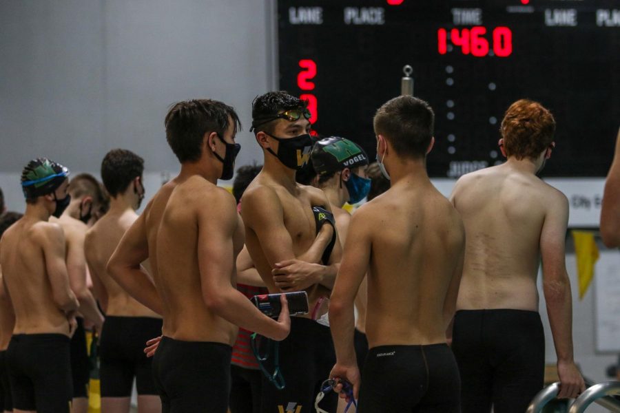 Trojan Bolt swimmers talk during the meet fully masked on Dec. 15 at the Coralville Rec Center.