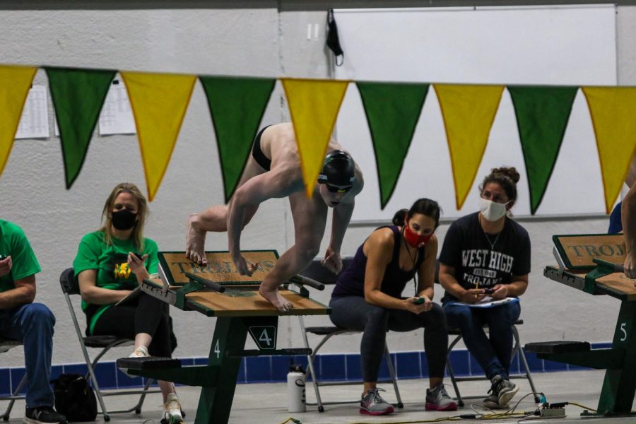 Kirk Brotherton '22 leaps off of the blocks at the start of the 50 Freestyle against Waterloo on Dec. 15 at the Coralville Rec Center.