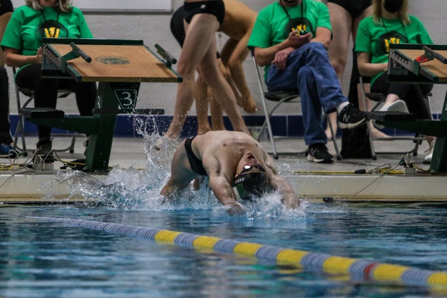 Boyd Skelley '22 flys off of the wall at the start of the 100 Backstroke against Waterloo on Dec. 15 at the Coralville Rec Center.