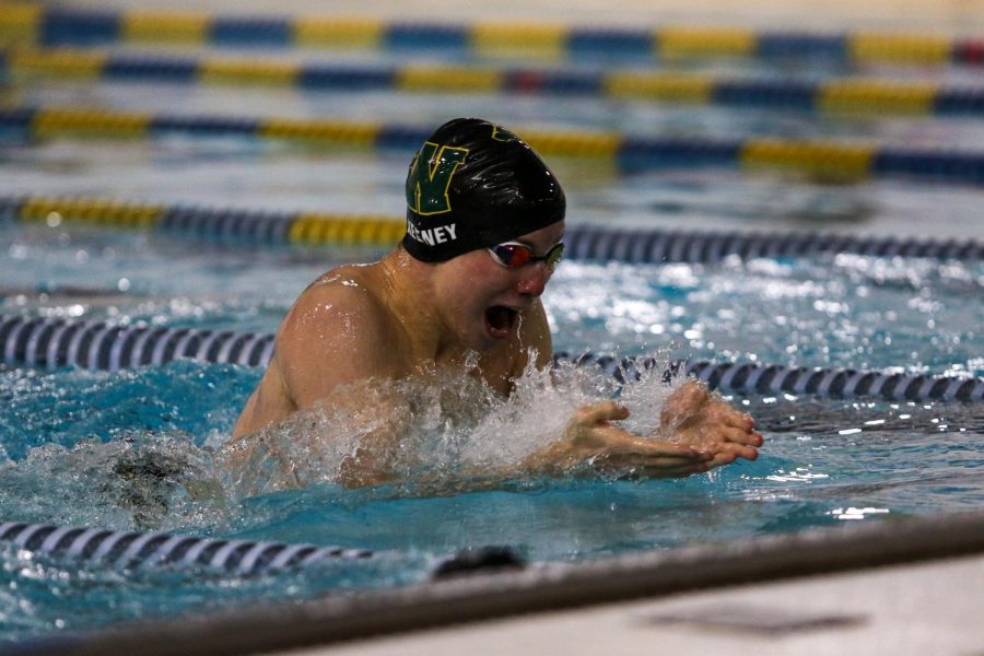 Gavin Keeney '22  takes a breath during the 100 Breaststroke against Waterloo on Dec. 15 at the Coralville Rec Center.