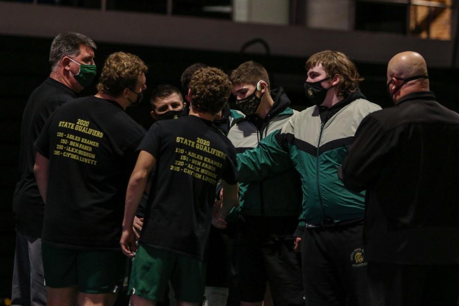 Coaches and captains shake hands while wearing face masks before wrestling on Jan. 21.