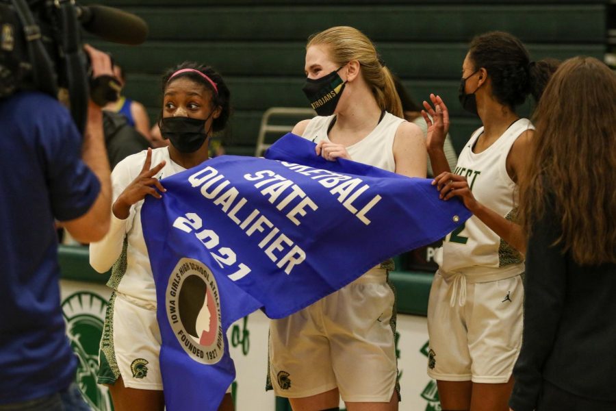 Matayia Tellis '21, Anna Prouty '23 and Meena Tate '23 celebrate with their banner after beating Davenport North and advancing to the state quarterfinals on Feb. 23.