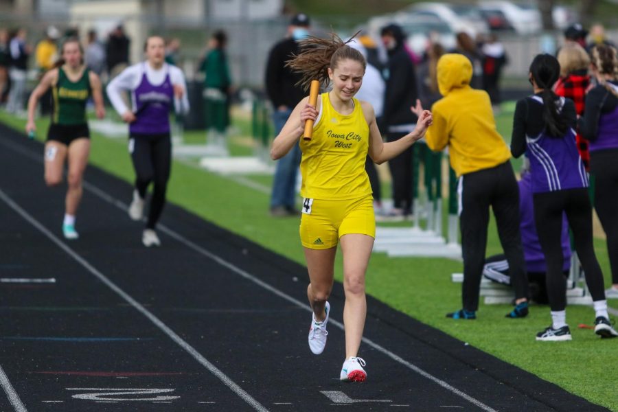 Vicki Carrica '23 celebrates as she crosses the finish line after running the final leg of the 4 by 800 meter relay during the Iowa City West Invitational on March 30.