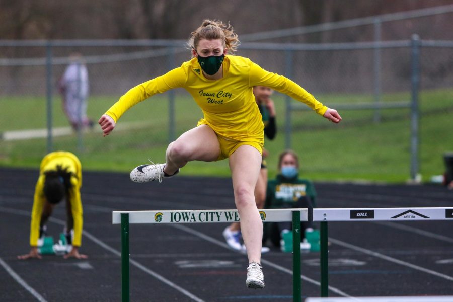 Raina Pfeifer '22 jumps over the first hurdle while competing in the shuttle hurdle relay during the Iowa City West Invitational on March 30.