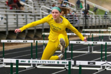 Ella Woods '22 glides over the hurdle while competing in the 100-meter hurdles during the Iowa City West Invitational on March 30.