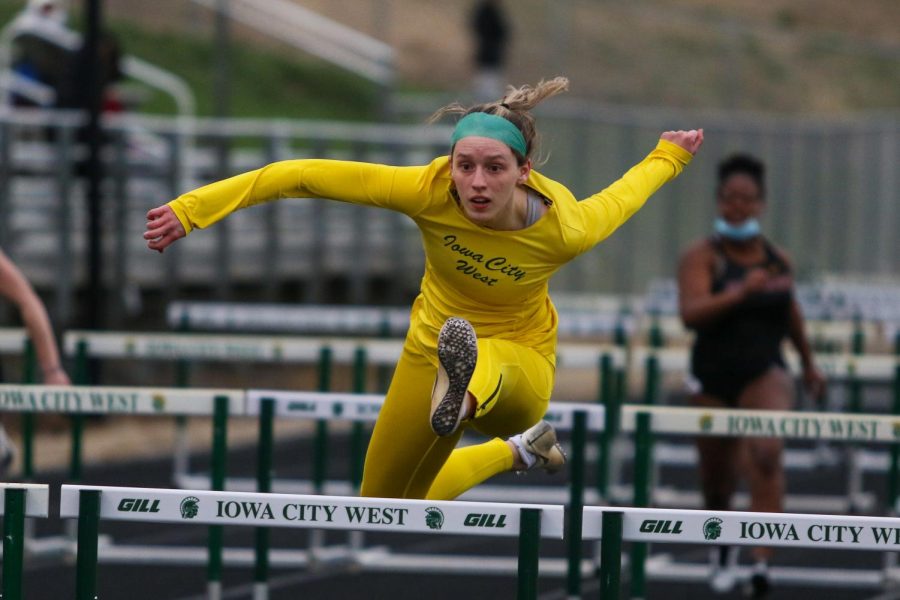 Ella Woods '22 glides over the hurdle while competing in the 100-meter hurdles during the Iowa City West Invitational on March 30.