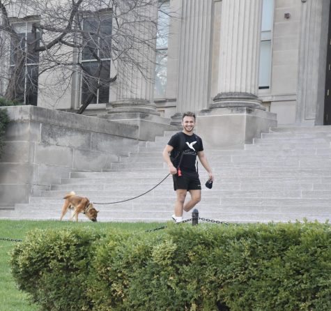 Holding his mask in one hand and walking his dog past Jessup Hall in downtown Iowa City, a man is happy to have his picture taken. Seconds later, he waved at the camera.