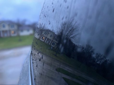 After a huge rainstorm, raindrops chase down a cars window, reflecting a house. Taken in Coralville Iowa after a big rainstorm.