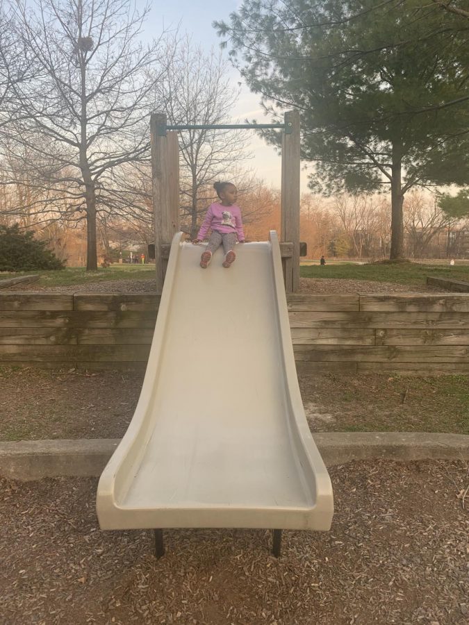 Reel Ibrahim is at the park, getting ready to launch down the slide while being careful not to slip down.


