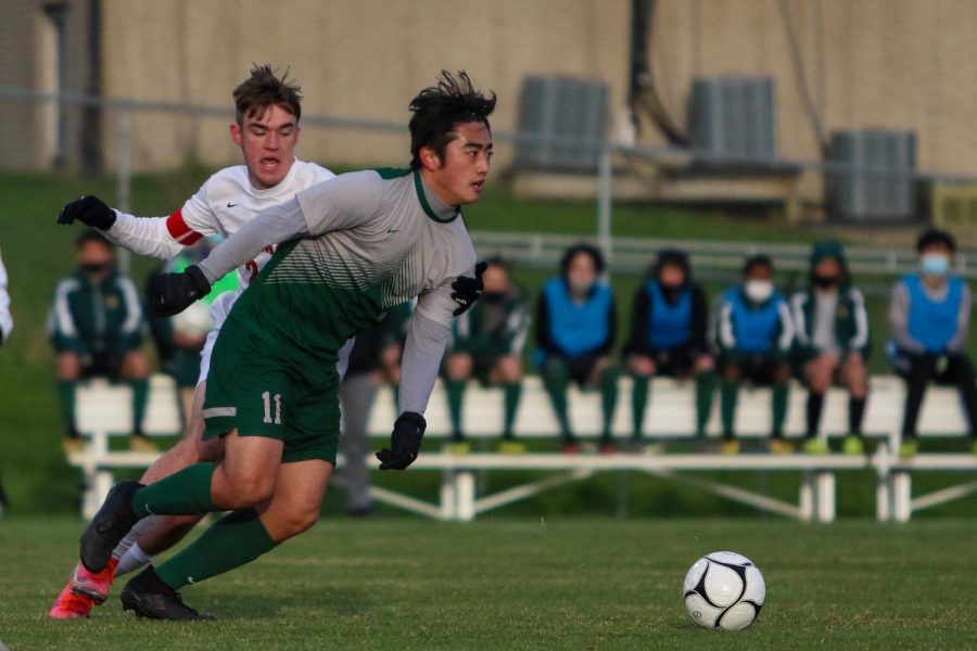 Yulong Shao '21 fights past his defender as he looks to pass ahead against Linn-Mar on April 20 at Ed Barker Field.