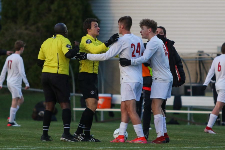 Linn-Mar players and both referees debate a call at the end of the first half on April 20 at Ed Barker Field.