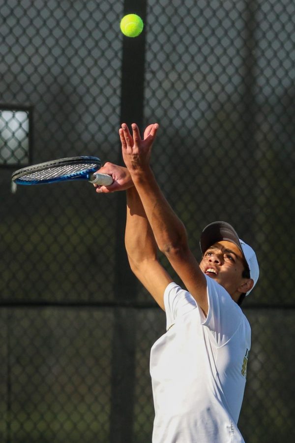 Luca Chackalackal '22 throws the ball into the air as he prepares to serve against City High at the Hawkeye Tennis and Recreation Center on April 29.