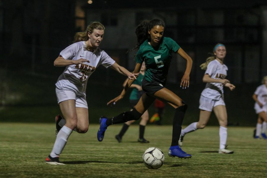 Meena Tate '23 looks for a steal while getting back on defense against Ankeny on April 6.