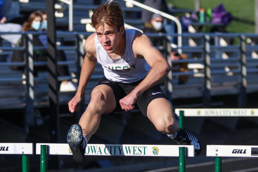 Clay Bopp '22 flies over a hurdle while competing in the shuttle hurdle relays during the Eastern Iowa Track and Field Festival on April 12.