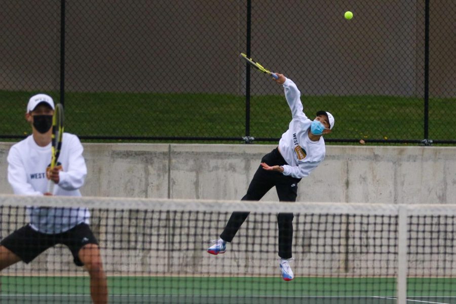 Jayden Shin '23 serves the ball while playing doubles against Cedar Rapids Washington on April 14.