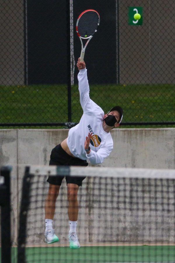 BJ Wolf '21 serves up an ace while playing doubles against Cedar Rapids Washington on April 14.