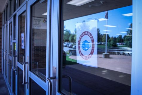 A sign taped to the West High front door tells students, staff and visitors about the new mandate on Sept. 15.