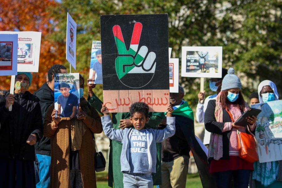 A young boy holds up a sign while protesting the military coup in Sudan at the Pentacrest in downtown Iowa City on Oct. 30. 