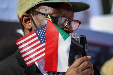 A man protesting the military coup in Sudan holds the American and Sudanese flag in his hand while addressing the crown at the Pentacrest in downtown Iowa City on Oct. 30. 