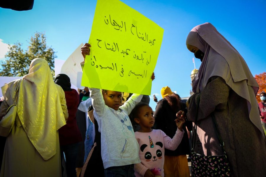 A young girl holds up a sign that reads “Abdel Fattah Al-Burhan (chairman of the military council) isn’t going to be Abdel Fattah Al-Sisi (president of Egypt) in Sudan'' as she protests the military coup in Sudan with her family on Oct. 30 at the Pentacrest in downtown Iowa City.