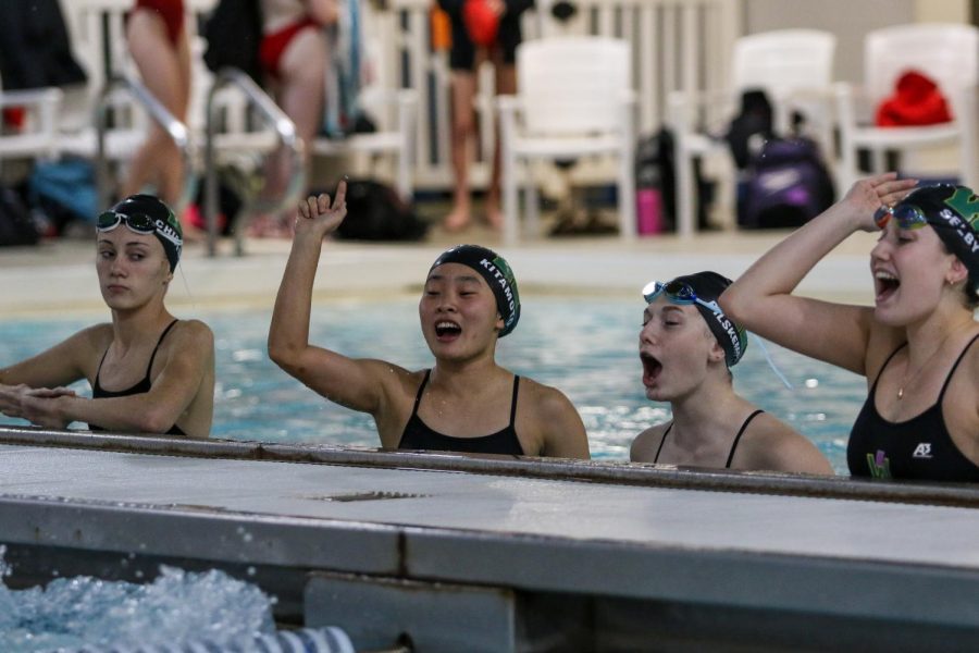 Hanah Kitamoto '22 and Emma Selby '22 cheer on their teammates from the warmup pool on Oct. 19 during a dual meet against City High.