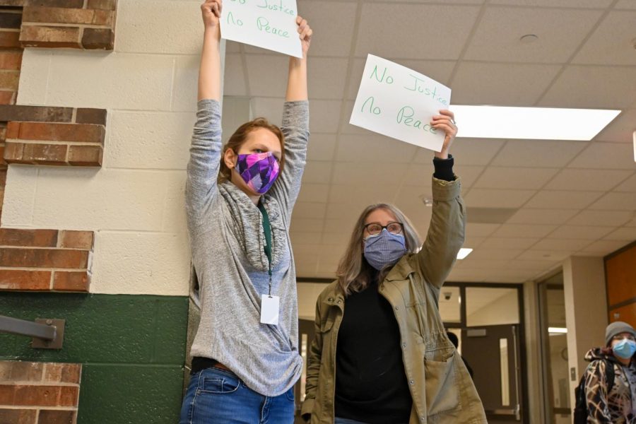 French teachers Heather Wacha and Katherine Jurak hold signs in solidarity with the student protesters during passing time.