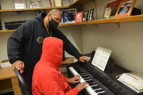 Donald Doyle watching over a student trying the piano during hip hop club meeting.  