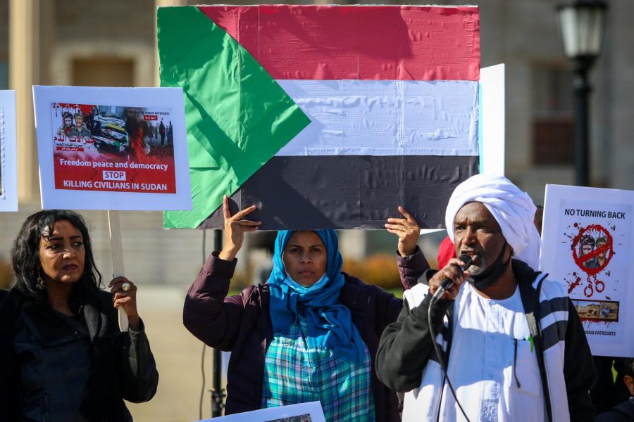 A woman lifts a sign with the Sudanese flag on it into the air while protesting the military coup in Sudan at the Pentacrest in downtown Iowa City on Oct. 30. 