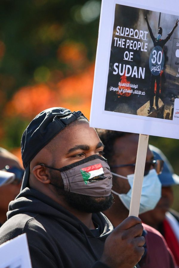 A man wears a facemask with the Sudanese flag on it while protesting the military coup in Sudan at the Pentacrest in downtown Iowa City on Oct. 30. 