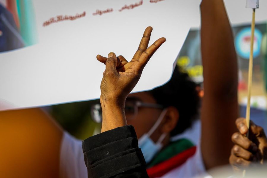 A protester holds up a peace sign while protesting the military coup in Sudan at the Pentacrest in downtown Iowa City on Oct. 30. 