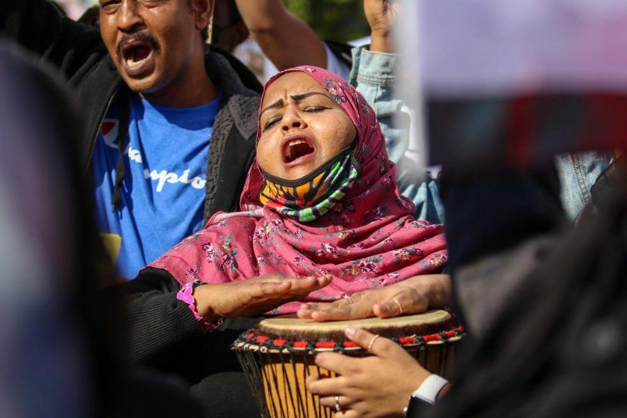 A woman chants and beats her drum while protesting the military coup in Sudan at the Pentacrest in downtown Iowa City on Oct. 30. 