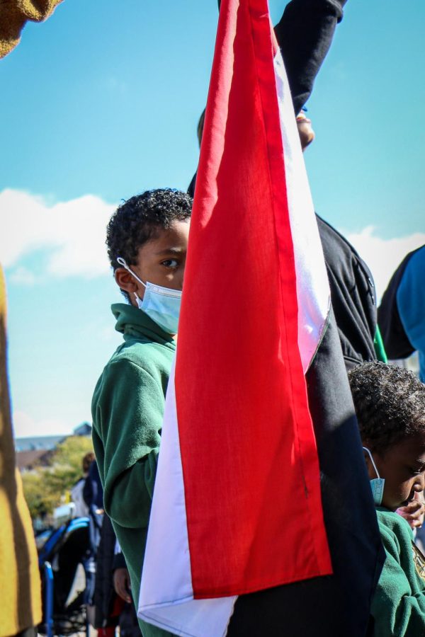 A young boy holds the Sundanese flag in his hand while protesting the military coup in Sudan at the Pentacrest in downtown Iowa City on Oct. 30. 
