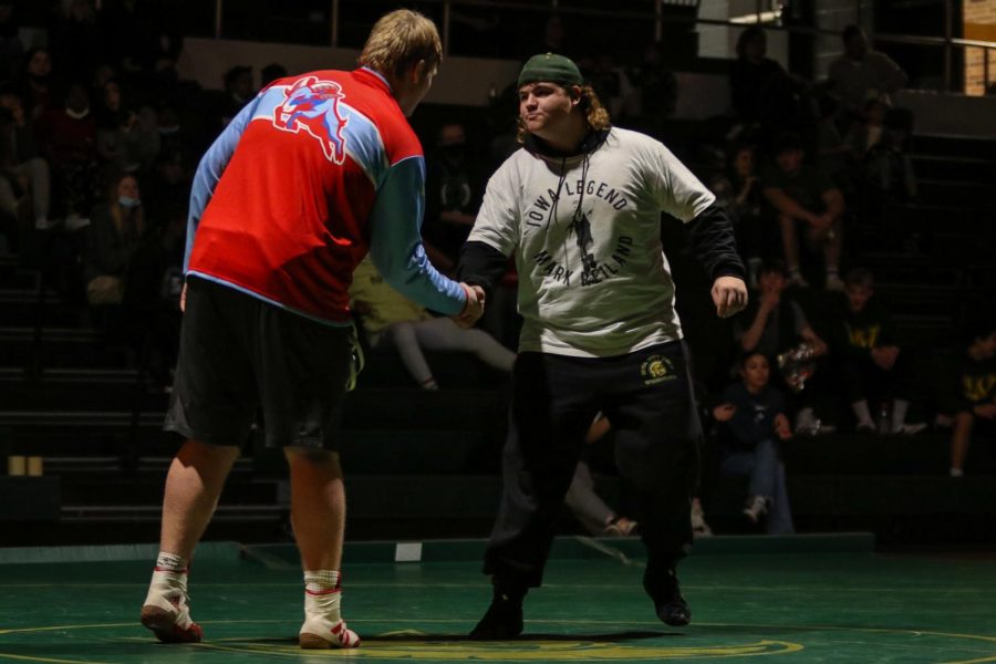 Brett Pelfry '22 shakes his opponent's hand wearing a shirt in remembrance of Mark Reiland before the dual meet against Dubuque Senior on Dec. 9 