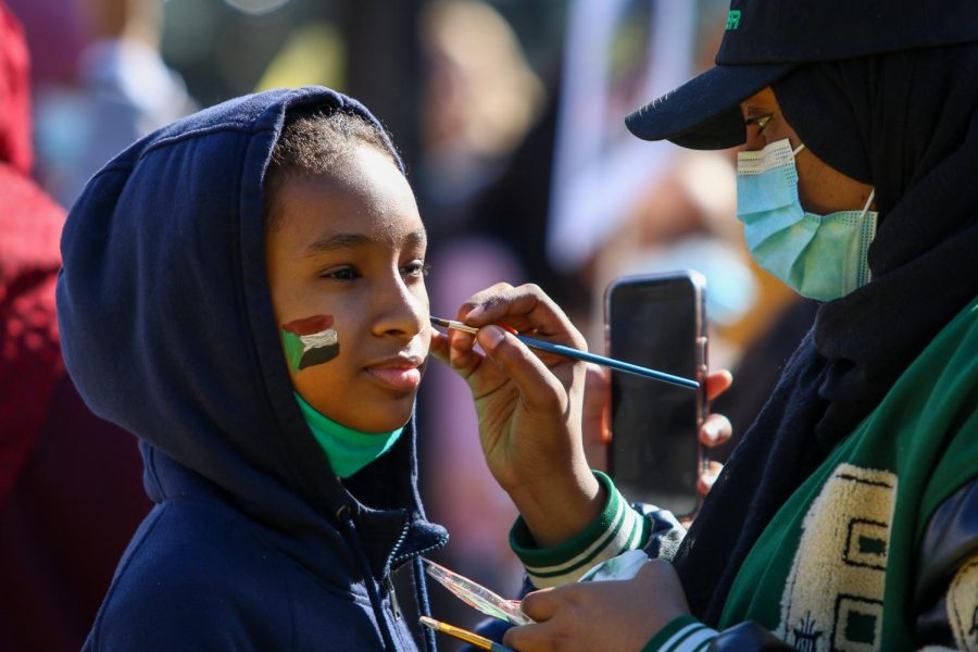 A young girls gets the Sudan flag painted on her face while protesting the military coup in Sudan at the Pentacrest in downtown Iowa City on Oct. 30. 