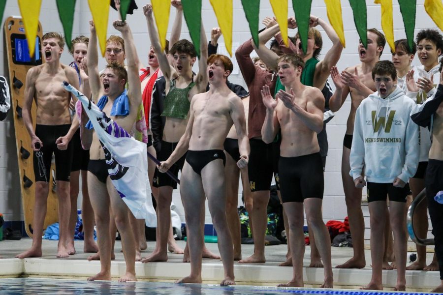 Kirk Brotherton 22 and the rest of the boys swim team celebrates the Trojan Bolts 400 yard freestyle relay win during a dual meet against Waterloo on Dec. 14, 2021.