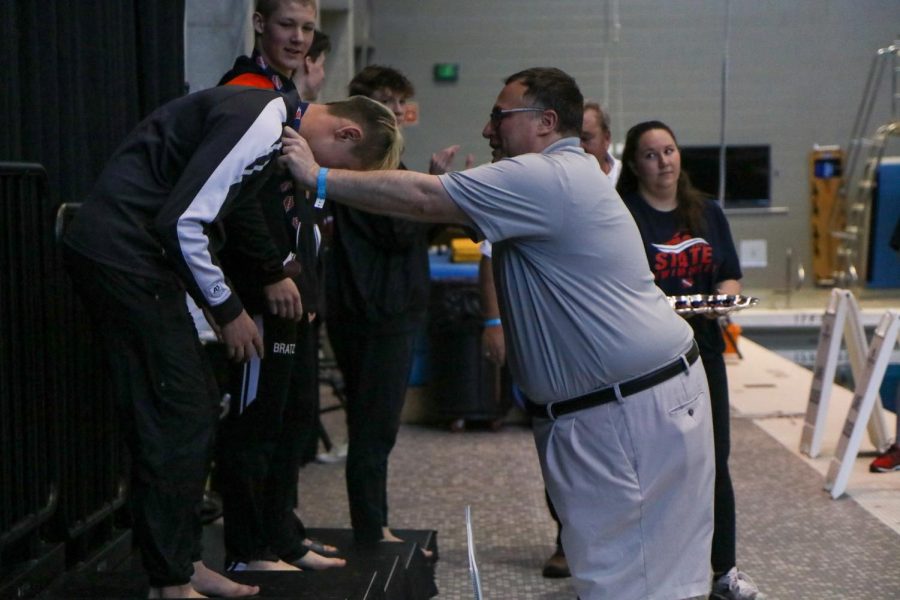 Holden Carter 24 recieves his medal after finishing fifth in the 100 meter butterfly final on Feb. 12.